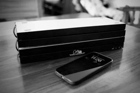 A black and white photo of a folding-piano folded down to a quarter of its length. It is shown next to an iPhone. When folded it is about double the length of the iPhone.