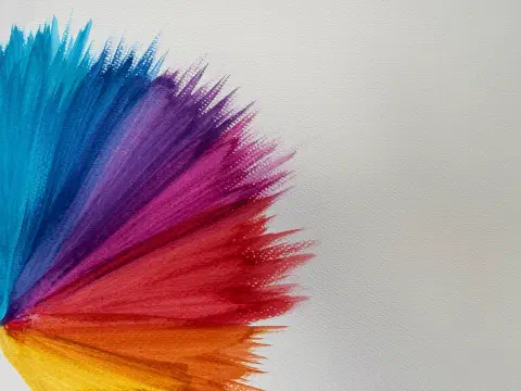 A burst of radial colour on watercolour paper. The colours range from blue, through purple, pink, red, orange and yellow.