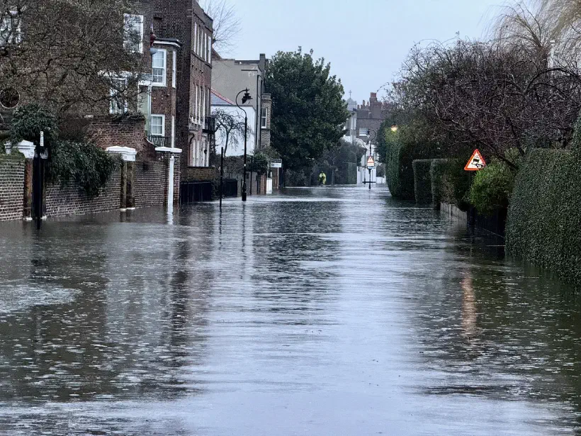 A photo of a flooded road. Flooding completely covers the road surface.