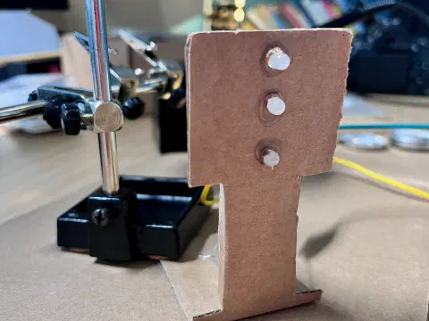 Photo showing a cardboard model of a traffic light with three LEDs for the red, amber, and green lights. All the LEDs are off.
