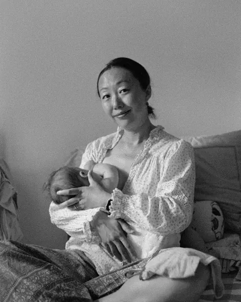 A black and white photo of a mother feeding a child, captured in Beijing on a Pentax MX on Ilford HP5+, developed at home in Ilfosol3 and scanned on a Plustek negative scanner.