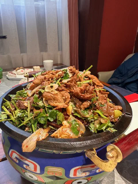 A close up photo of a pot containing sliced lamb, coriander and cumin.
