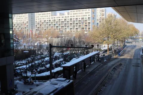 A photo taken inside an underpass in Beijing China. It is winter and there is snow on the ground beside the road.