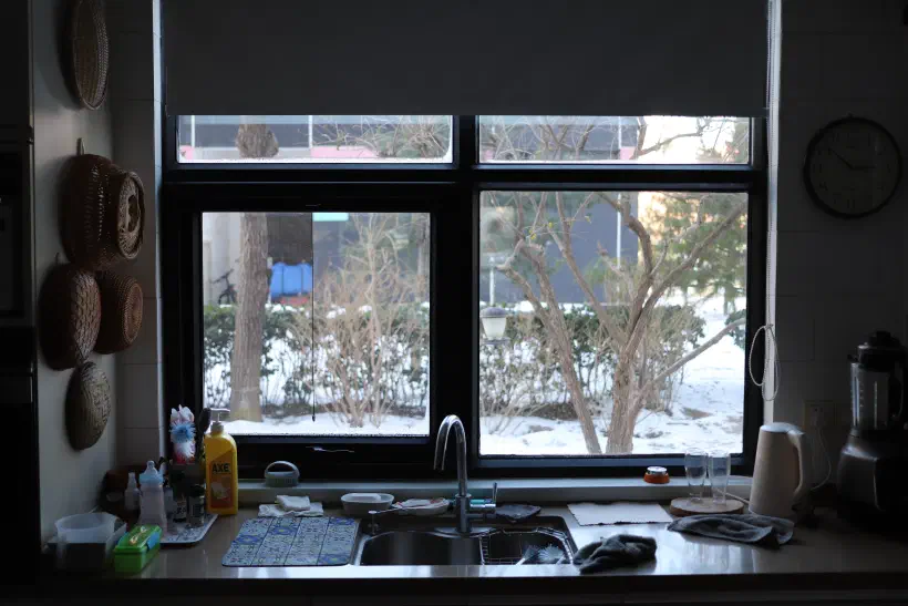 Looking out over a kitchen counter to a snow covered yard outside.
