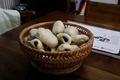 A basket full of freshly steamed date buns on a table.