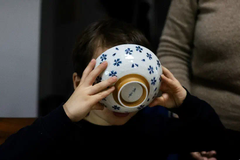 A child holds a bowl up to their face, drinking every last drop of the contents. The child's face is not visible.