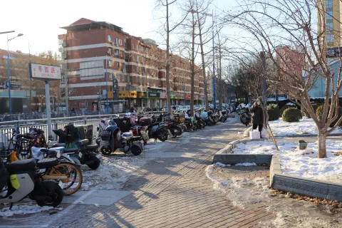 Bikes parked on the footpath outside a subway station. The ground is covered in snow.