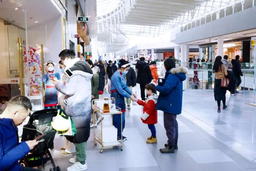 The scene outside a restaurant, a person and a child are handed a drink by one of the staff.