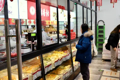 A person stands at the counter in a bakery in front of them an array of baked goods.