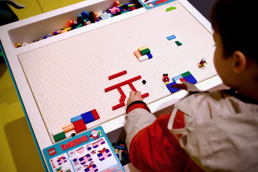 A child uses LEGO bricks to make Chinese characters on a table.