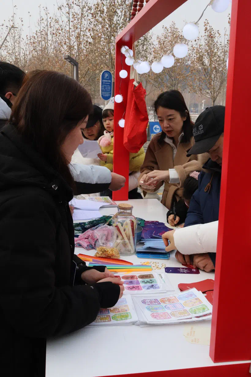 People crowd around a table to write their new years wishes on pieces of paper.