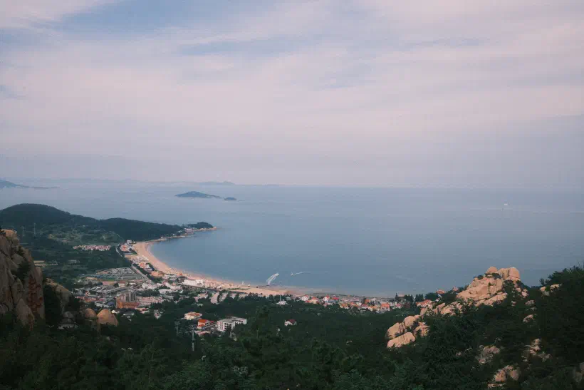 A colour photograph taken from the top of a mountain looking out over a bay