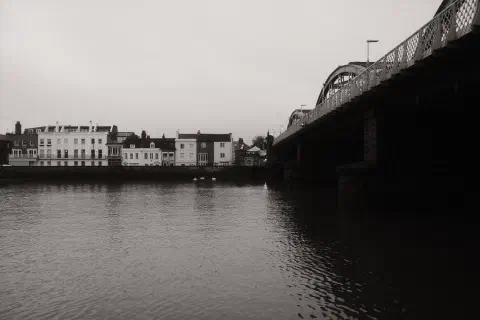 a black and white photo looking over the River Thames towards Barnes Bridge station