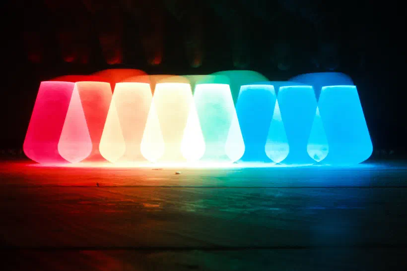 a long exposure image shows the blurred outline of a lightbulb moving across the image changing from red to blue as it does