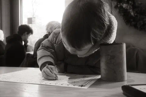 a young boy hunched over a piece of paper, a blunt crayon in one hand