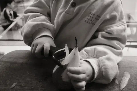a young child peels the skin off a pear