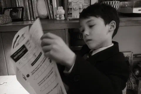 black and white photo of a boy looking at maths homework