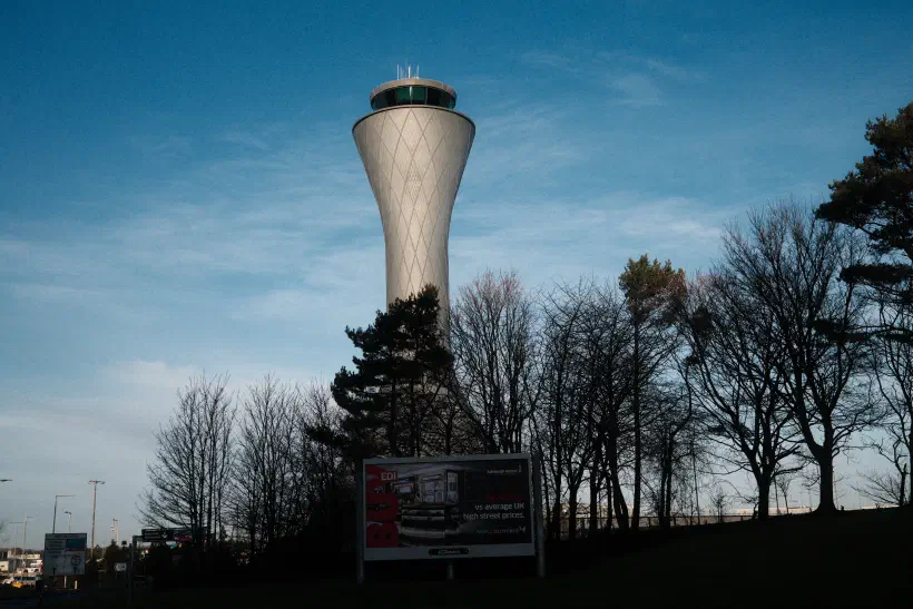 an air traffic control tower stands above an advert for Edinburgh Airport