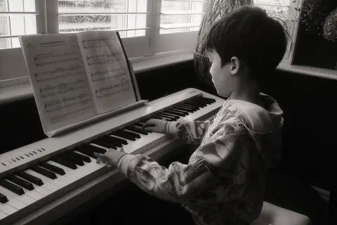 a black and white photo of a boy playing the piano