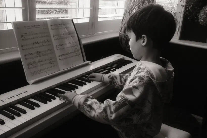 a black and white photo of a boy playing the piano