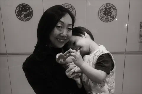 a black and white photo of a mother and child, in the background Chinese New Year decorations