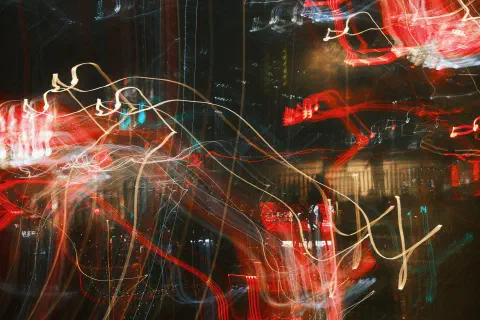 A blurred mess of light streaks across a nighttime city photo, the dominate colours are red, white, and black.
