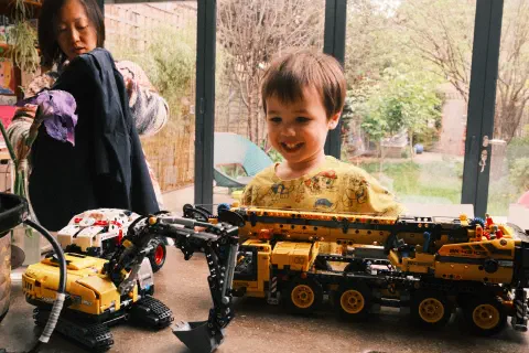 a young boy looks at a collection of Lego Technic models, a smile on his face