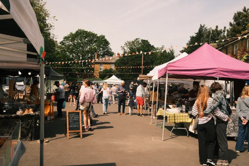 a small paved area lined by market stalls, bunting strung up between the stalls