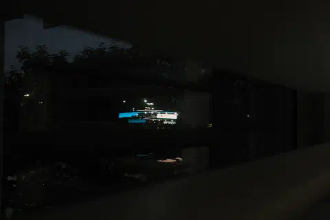 a photo of a night time reflection in an office window, the reflection shows a desk lit up by a computer monitor